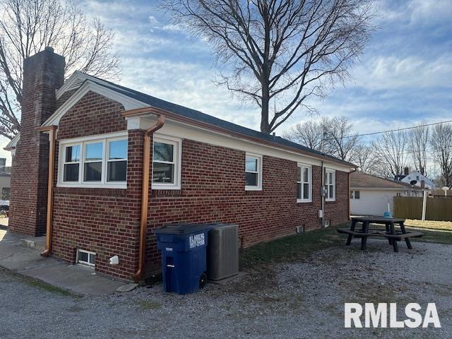 view of side of property featuring brick siding and a chimney