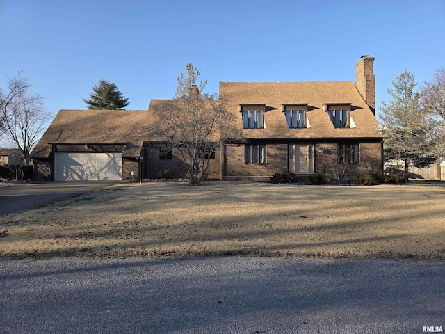 view of front of house with a garage, driveway, a chimney, and a front yard