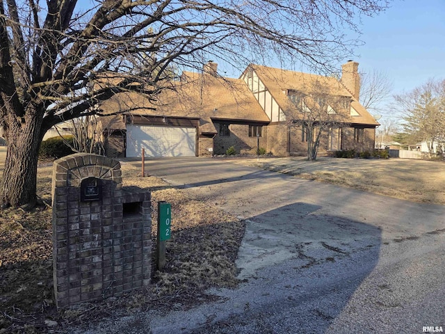 view of front of property with a garage, concrete driveway, a chimney, and stucco siding