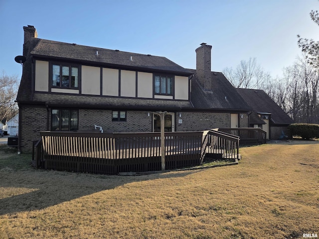 rear view of property featuring a deck, brick siding, a lawn, and a chimney