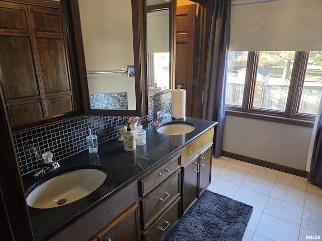 bathroom with baseboards, double vanity, a sink, and decorative backsplash