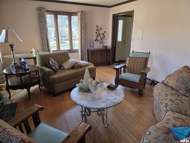 living area with light wood-type flooring and ornamental molding