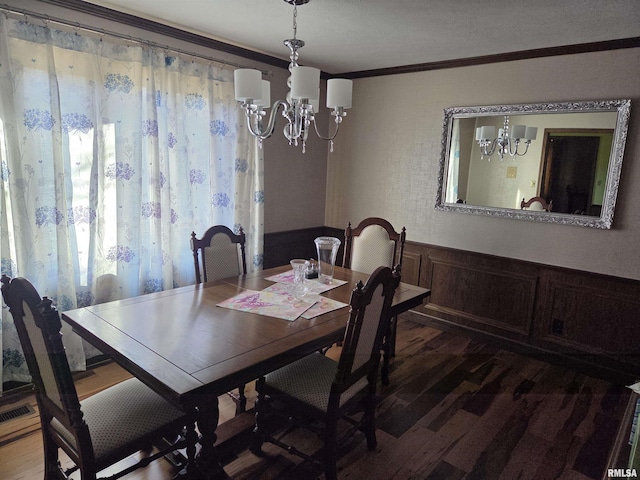 dining room with a chandelier, a wainscoted wall, dark wood-style flooring, visible vents, and crown molding