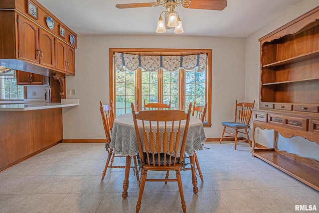 dining space with a ceiling fan, baseboards, and light tile patterned floors