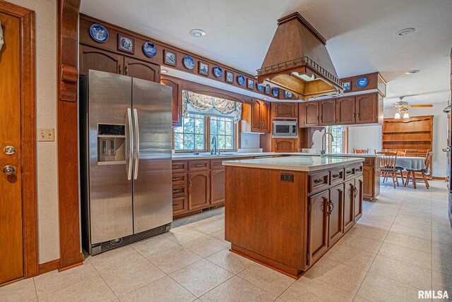 kitchen featuring a center island with sink, light tile patterned floors, stainless steel appliances, light countertops, and a sink