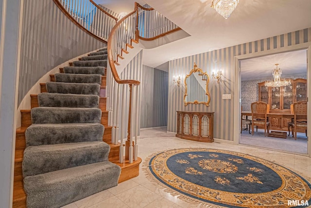 stairs featuring wallpapered walls and a notable chandelier