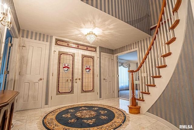 entrance foyer featuring french doors, marble finish floor, wallpapered walls, baseboards, and stairs