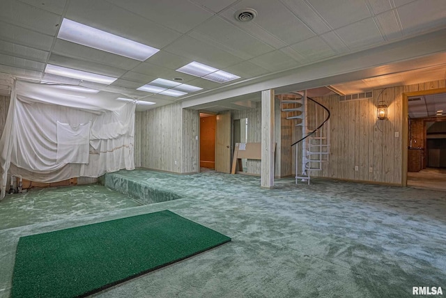 below grade area with carpet floors, wood walls, stairs, and visible vents