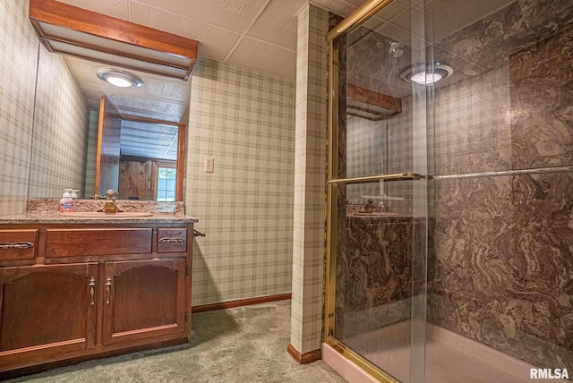 bathroom with vanity, a shower stall, baseboards, and wallpapered walls