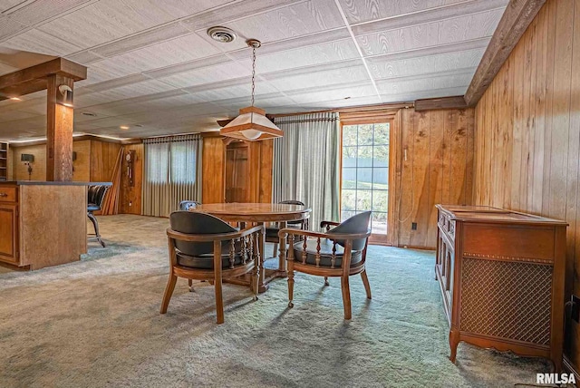 carpeted dining area with visible vents and wooden walls