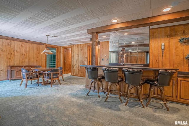 bar featuring pendant lighting, carpet floors, indoor wet bar, and wooden walls