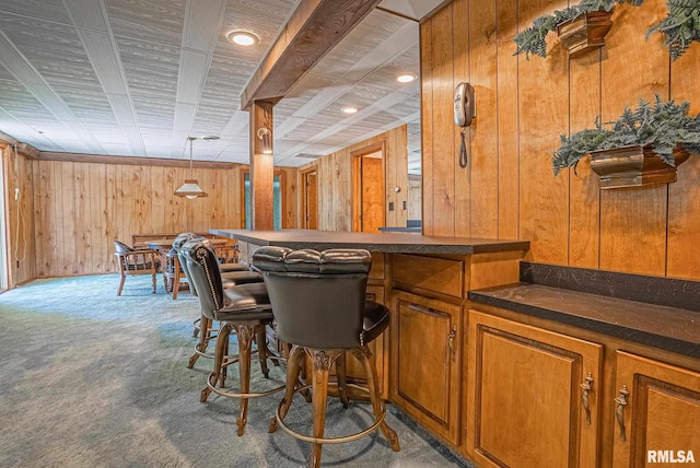 bar with carpet, decorative light fixtures, wood walls, and a dry bar