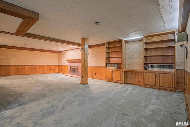 interior space featuring wooden walls, wainscoting, visible vents, and a brick fireplace