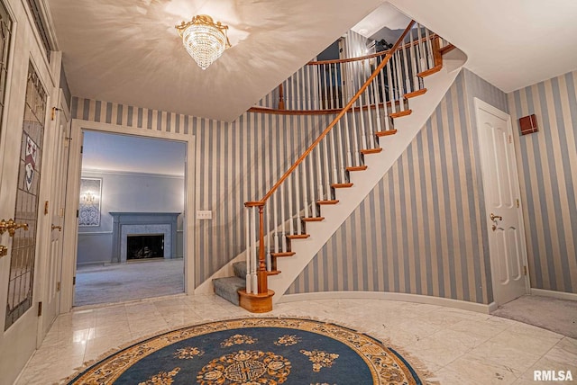 stairway featuring marble finish floor, a fireplace, baseboards, and wallpapered walls