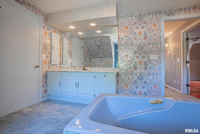 full bath featuring a bath, vanity, and wallpapered walls