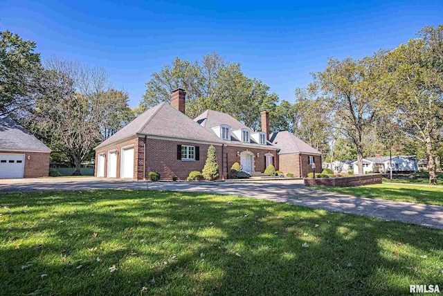 view of front of property featuring a garage, driveway, a front lawn, and brick siding