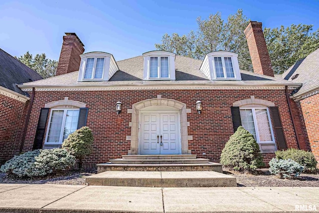 view of front of property featuring roof with shingles, a chimney, and brick siding