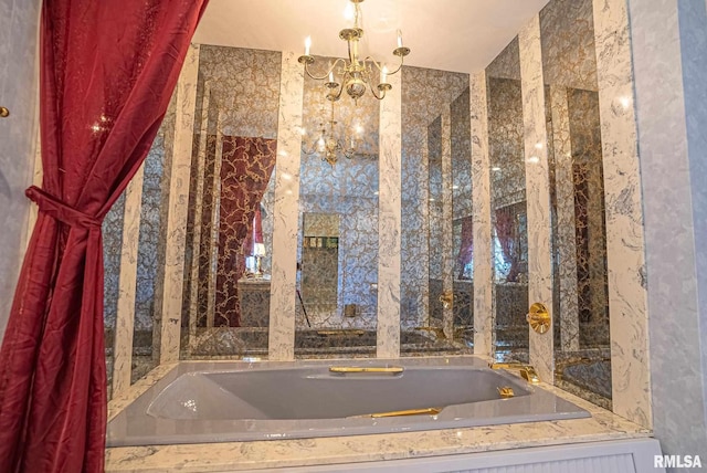 bathroom with a garden tub and a notable chandelier