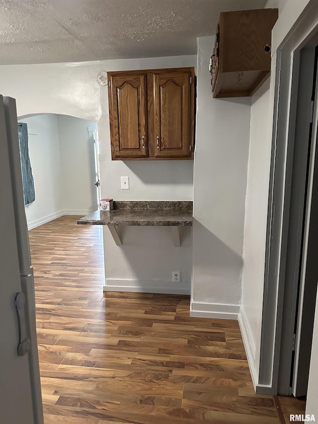 kitchen featuring dark countertops, wood finished floors, freestanding refrigerator, and a textured ceiling