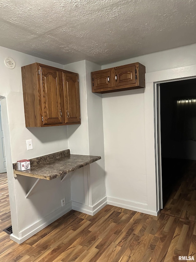 interior space featuring visible vents, baseboards, a textured ceiling, and wood finished floors