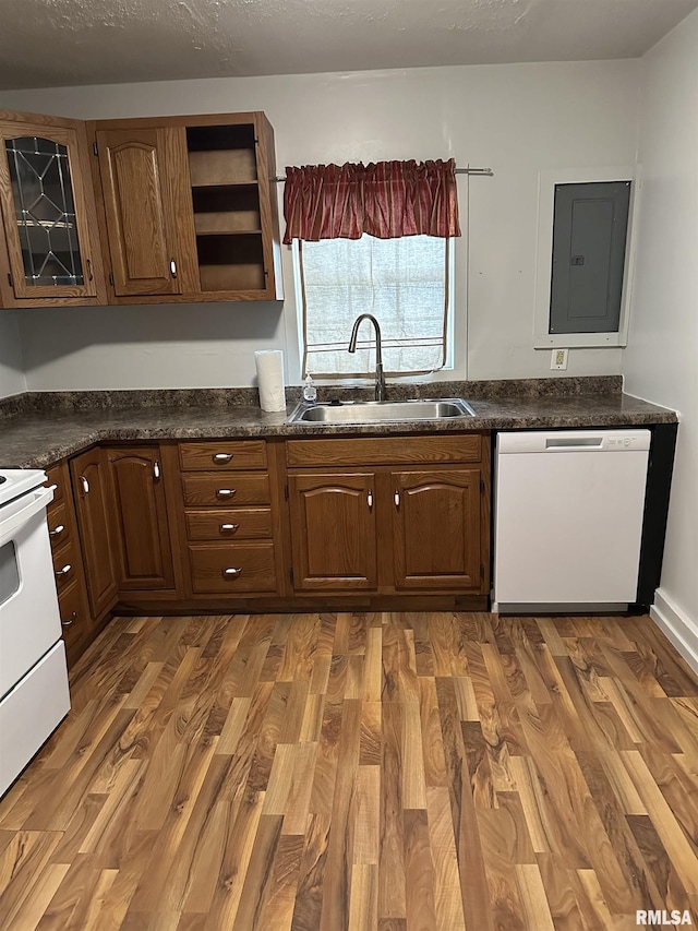kitchen with a sink, white appliances, dark countertops, and electric panel