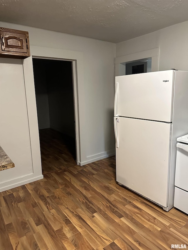 kitchen featuring a textured ceiling, wood finished floors, freestanding refrigerator, baseboards, and stove