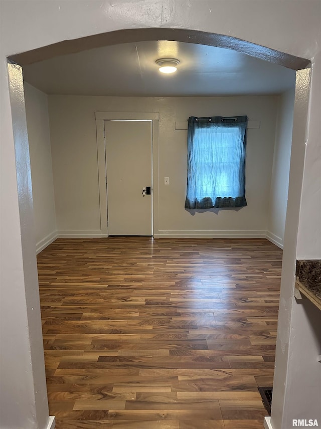spare room with baseboards and wood finished floors