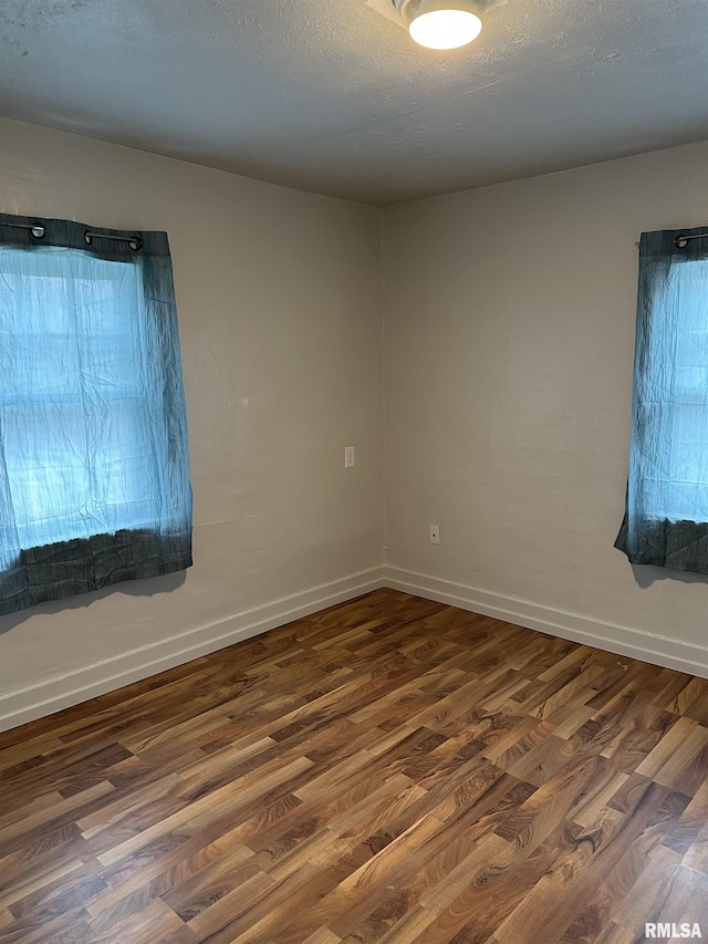 unfurnished room featuring a textured ceiling, baseboards, and wood finished floors