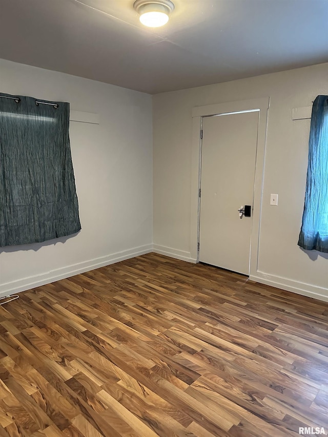 unfurnished room featuring visible vents, baseboards, and wood finished floors