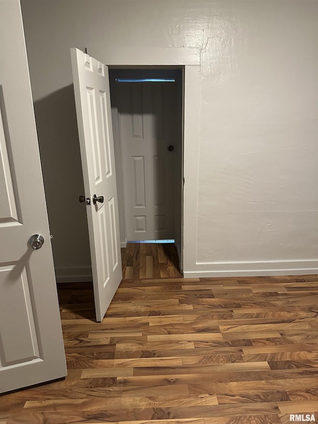 corridor featuring baseboards and wood finished floors