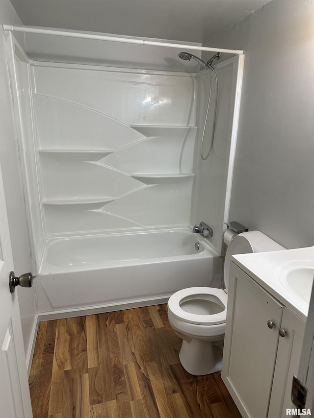 bathroom with toilet, vanity,  shower combination, and wood finished floors