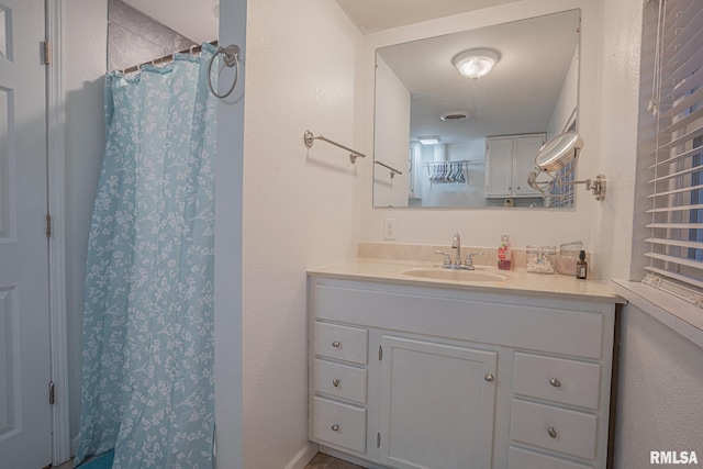 full bathroom featuring a shower with shower curtain, vanity, and visible vents