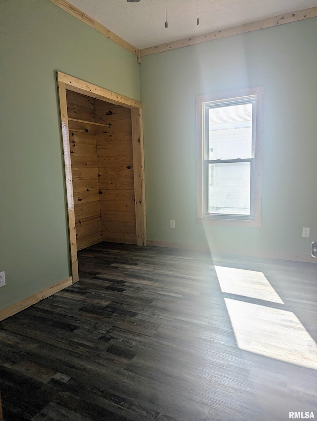 spare room with dark wood finished floors, baseboards, and ceiling fan