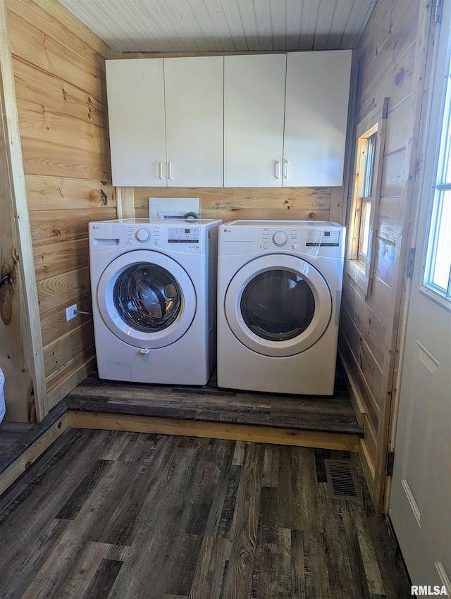 laundry room featuring wood walls, visible vents, cabinet space, dark wood-style floors, and washer and clothes dryer