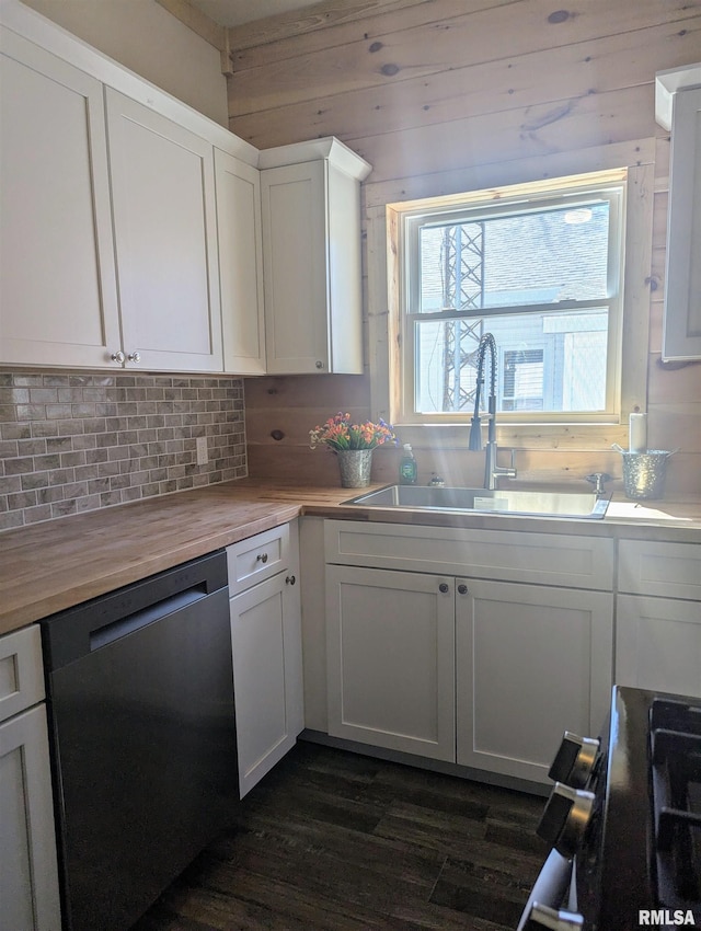 kitchen with dishwashing machine, wood counters, a sink, white cabinetry, and backsplash