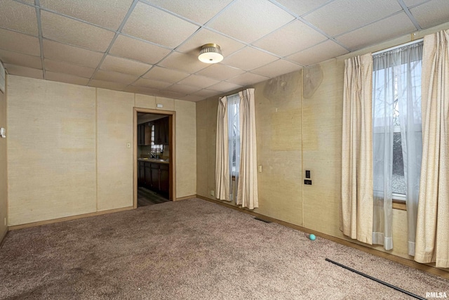 carpeted empty room featuring a paneled ceiling