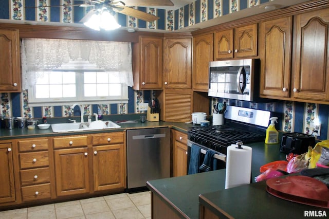 kitchen with appliances with stainless steel finishes, brown cabinets, a sink, and wallpapered walls