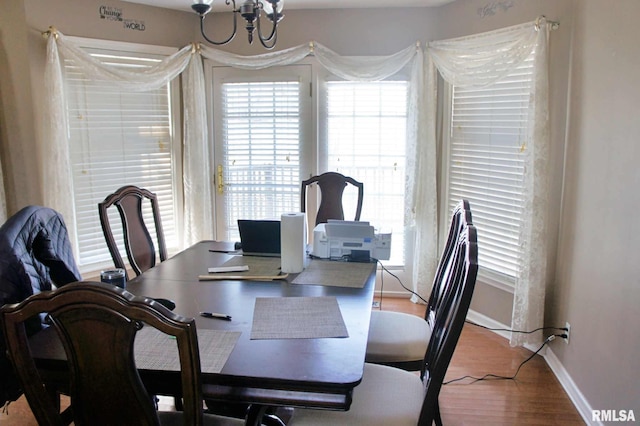 dining space with an inviting chandelier, baseboards, and wood finished floors