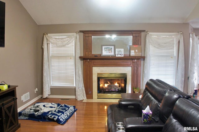 living room featuring visible vents, baseboards, wood finished floors, vaulted ceiling, and a fireplace