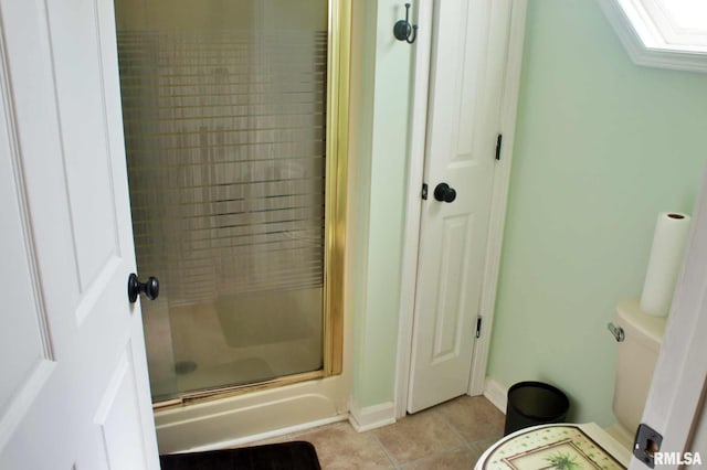 bathroom featuring toilet, a skylight, baseboards, tile patterned floors, and a stall shower