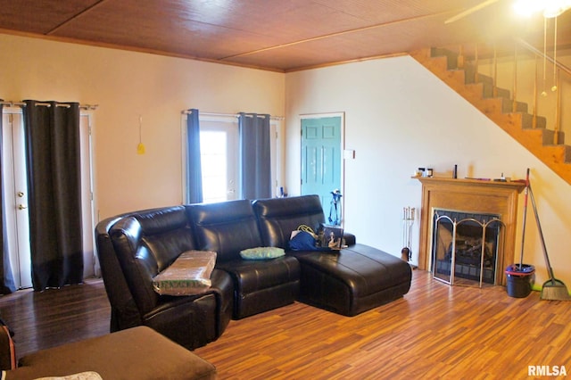 living room featuring wooden ceiling, a fireplace with flush hearth, stairway, and wood finished floors