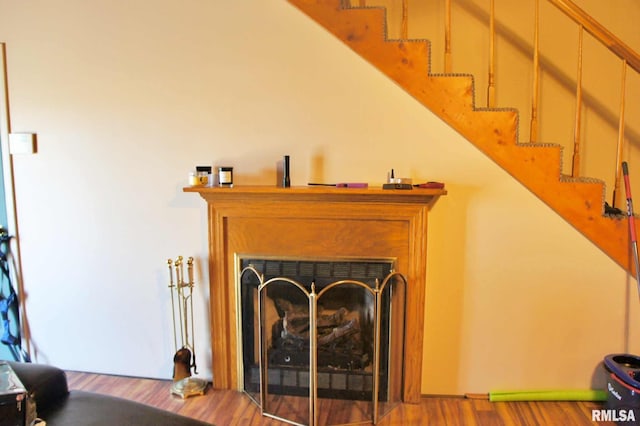 living area with a fireplace, stairway, and wood finished floors