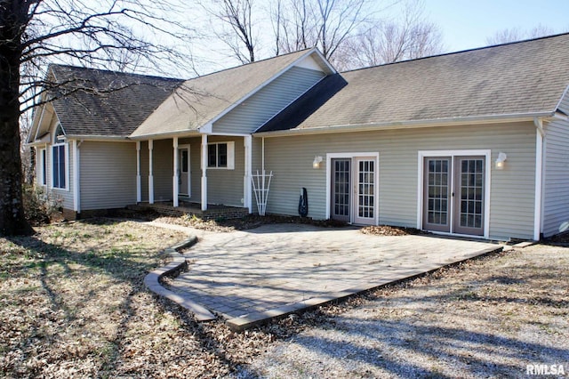 rear view of property featuring a shingled roof, a patio area, and a porch