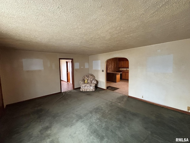 interior space featuring arched walkways, baseboards, a textured ceiling, and carpet