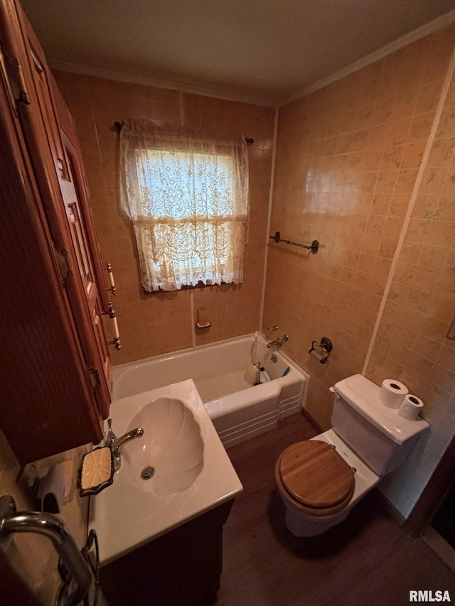 bathroom featuring toilet, ornamental molding, a bathtub, vanity, and tile walls