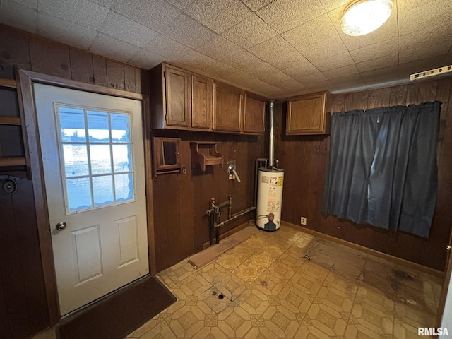 interior space with laundry area, light floors, gas water heater, and wooden walls