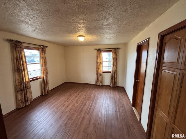 unfurnished room featuring a textured ceiling, baseboards, and wood finished floors