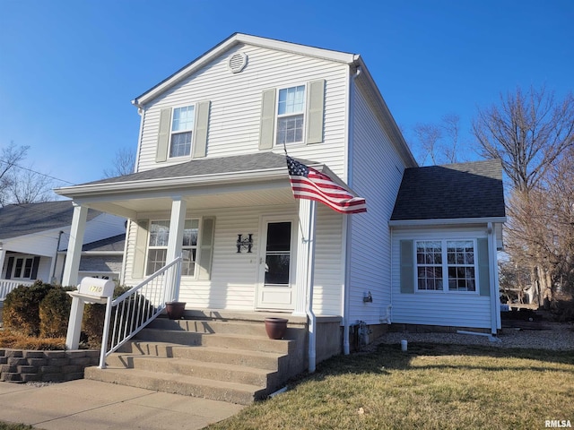 traditional-style house featuring covered porch, roof with shingles, and a front lawn