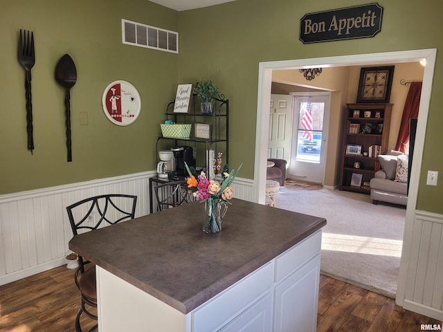 dining room featuring dark wood-type flooring, wainscoting, and visible vents