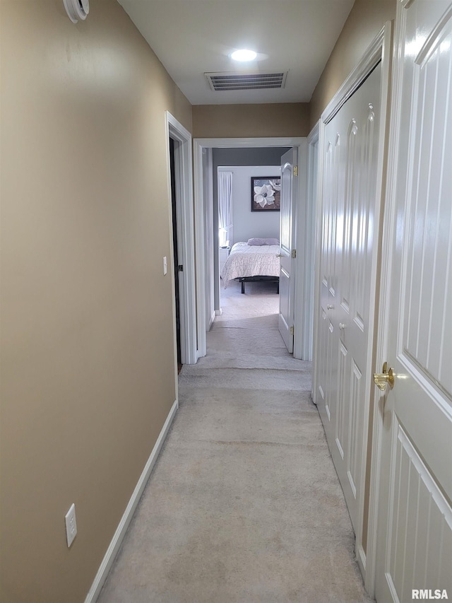 hall featuring visible vents, light carpet, and baseboards